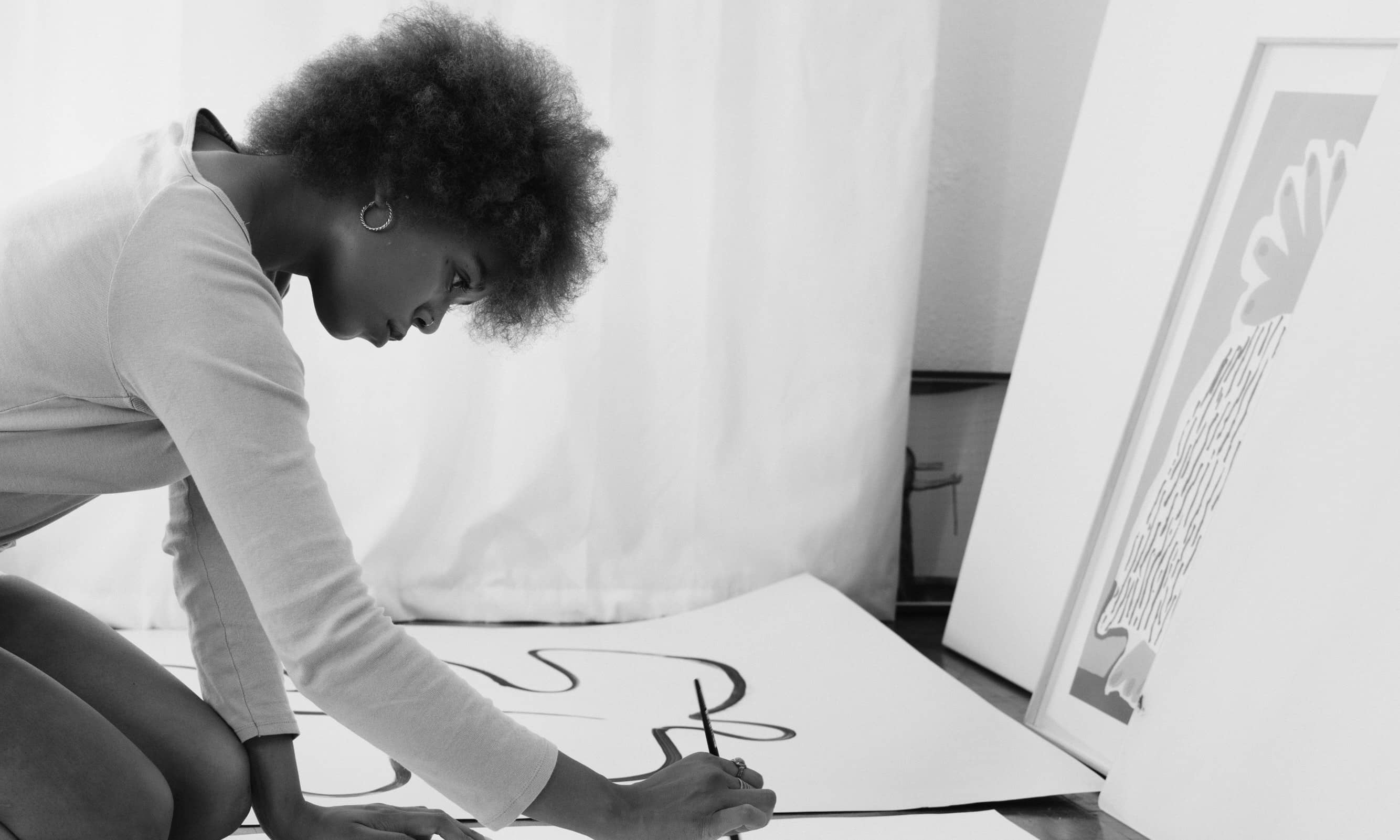 A black and white image of a women drawing on a big canvas